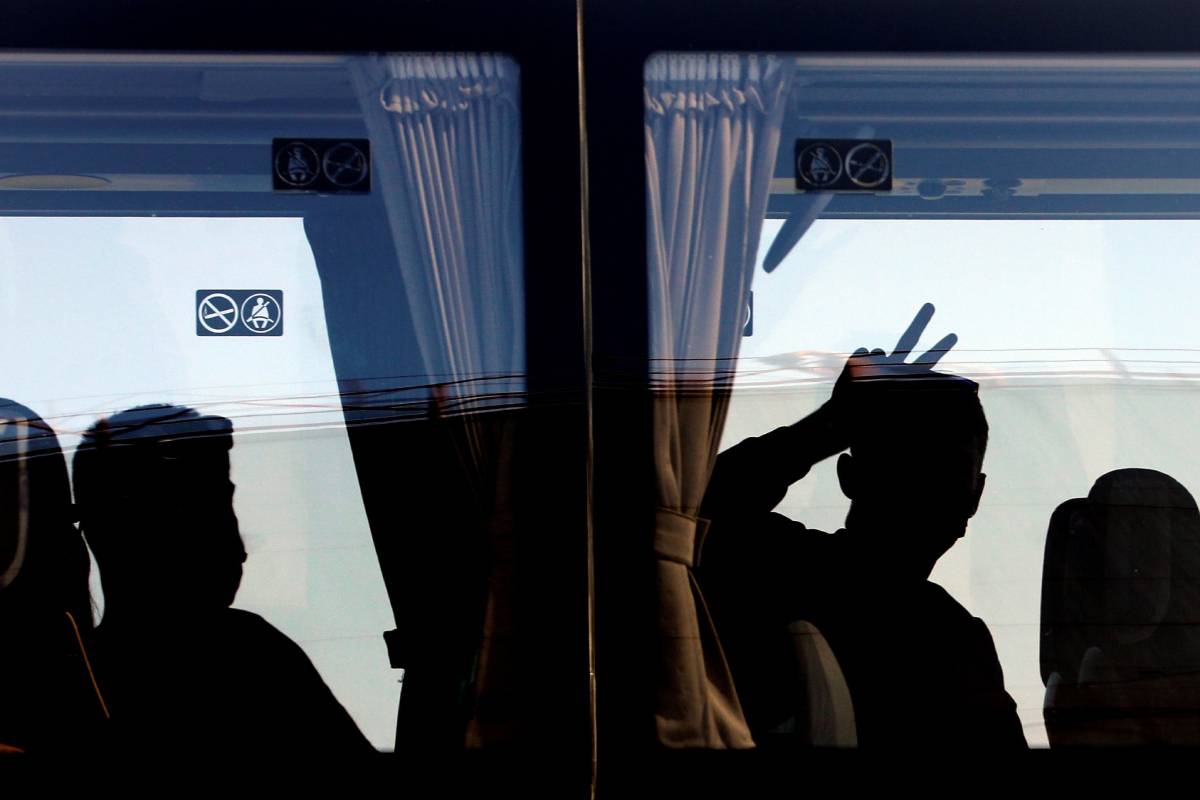 Una persona saluda desde el autobús tras desembarcar del ferry en el que viajaban 118 estudiantes que habían sido confinados en un hotel de Mallorca tras el macrobrote detectado en la isla. (Foto: EFE/Ana Escobar)
